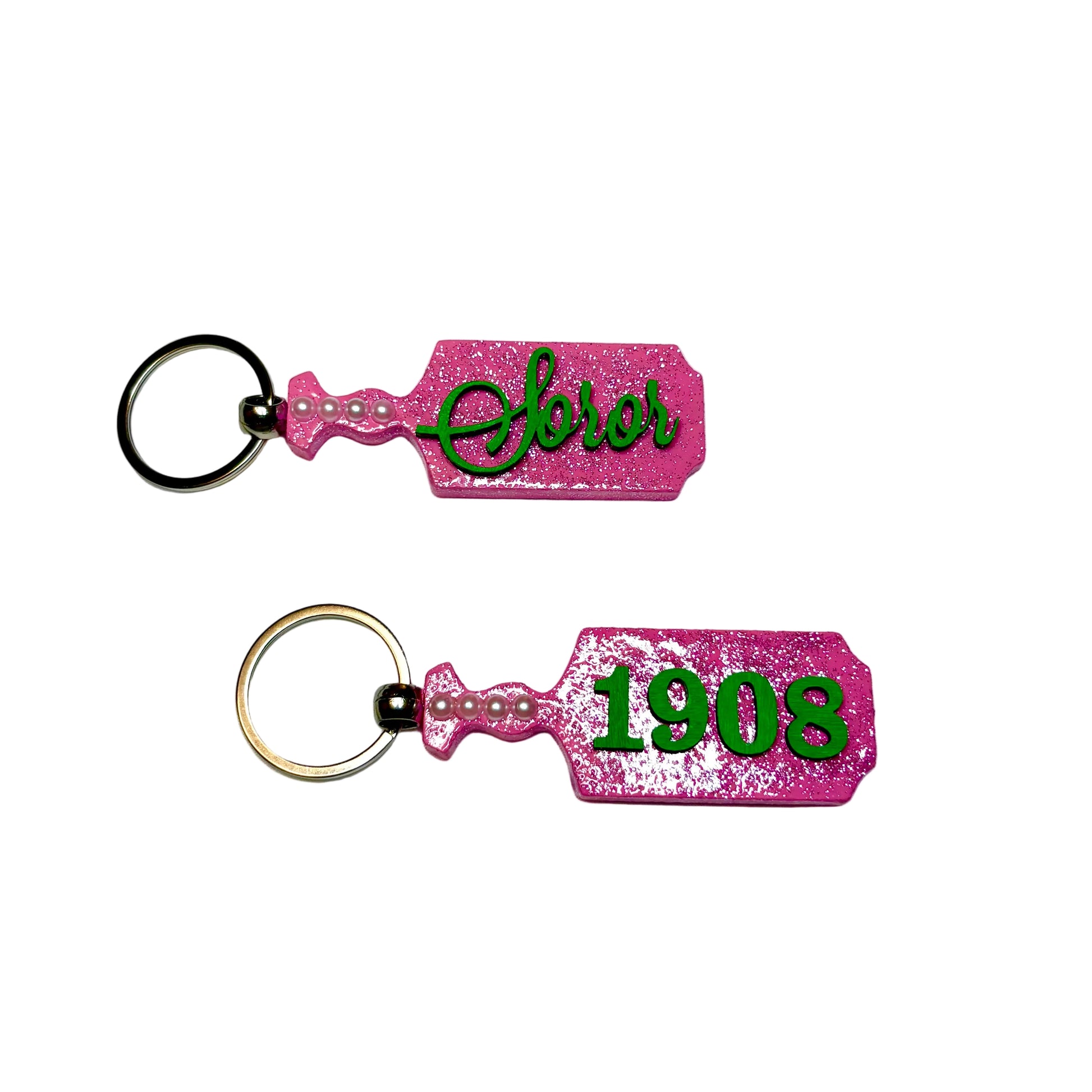Two pink keychains with green text on a white background